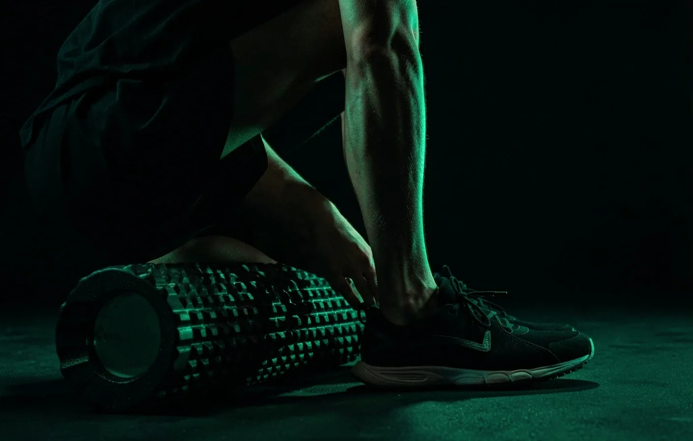 Athlete using a textured foam roller on calf muscles in a studio